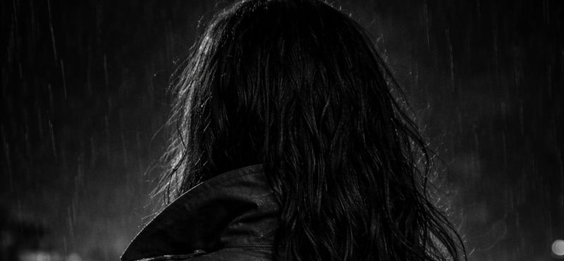 Black and white image of a dark haired woman seen from the back.